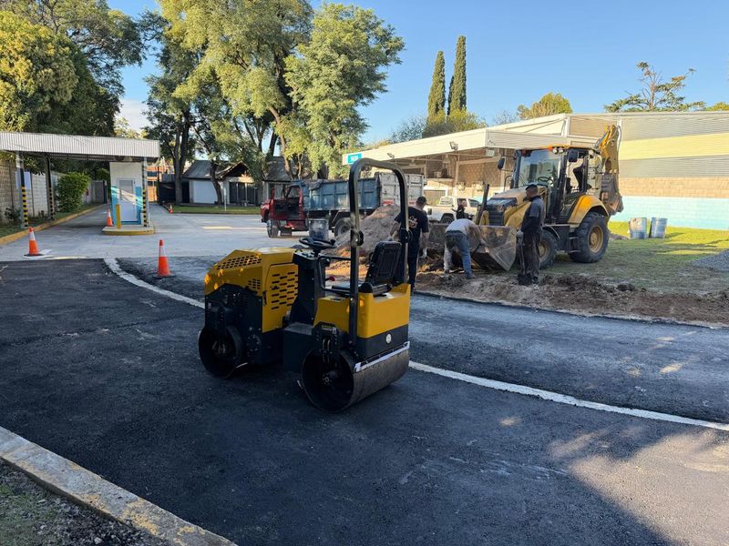 Rodillo compactador y retroexcavadora CAT trabajando en asfaltado