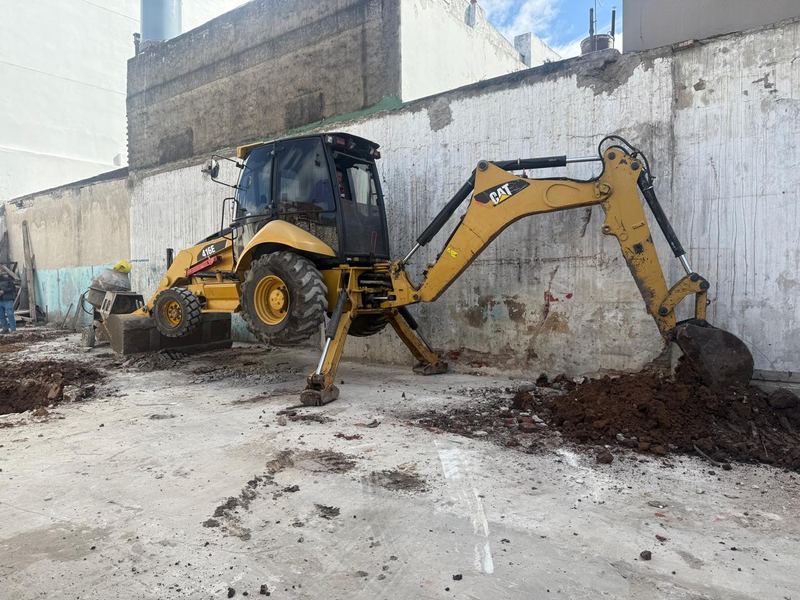Retroexcavadora CAT 416E excavando terreno en obra urbana